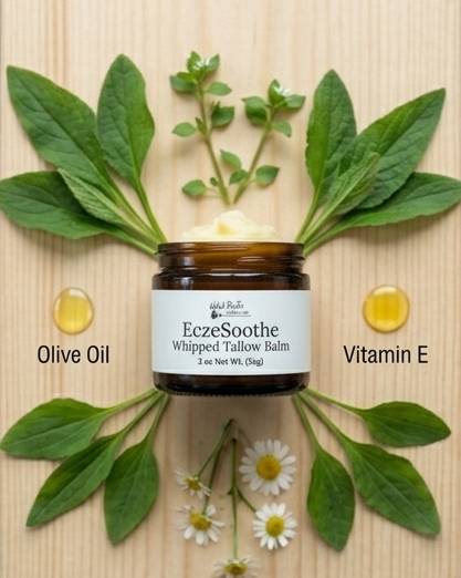 Jar of Eczesothe Whipped Tallow Balm surrounded by green leaves and flowers on a wooden background