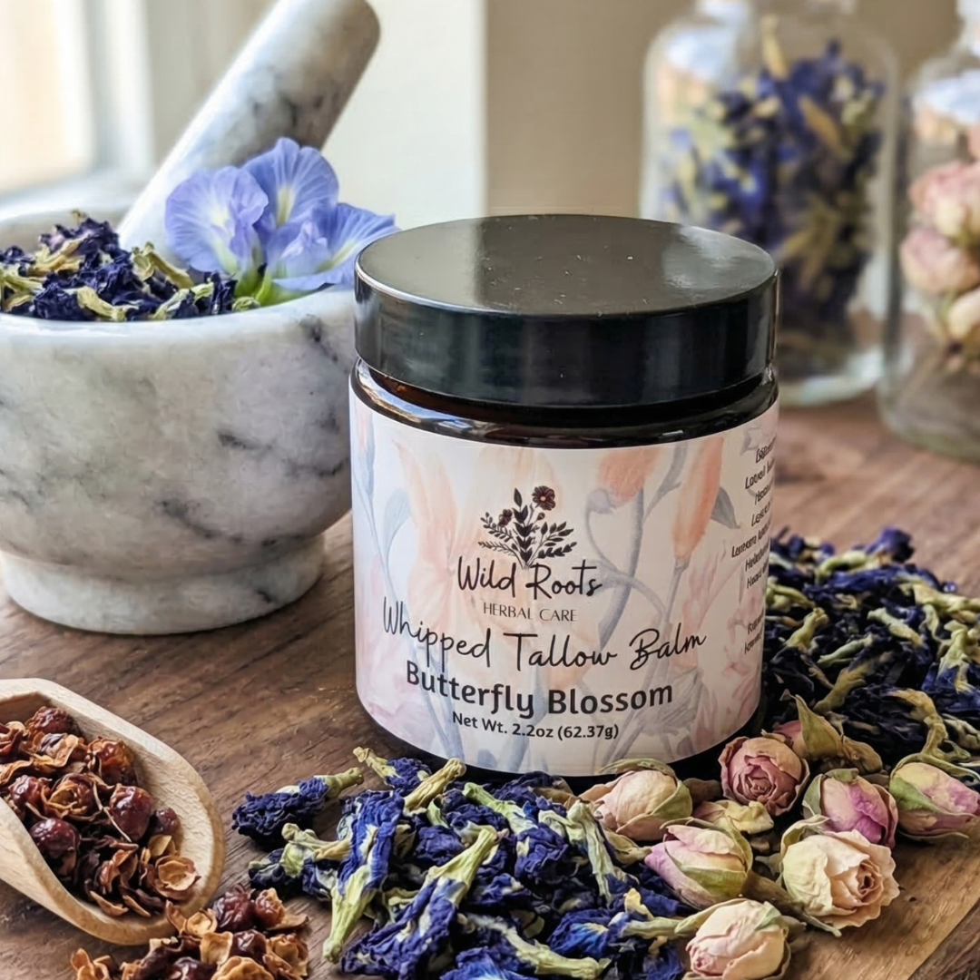 Whipped tallow balm jar labeled 'Butterfly Blossom' on a wooden surface with dried flowers and herbs.