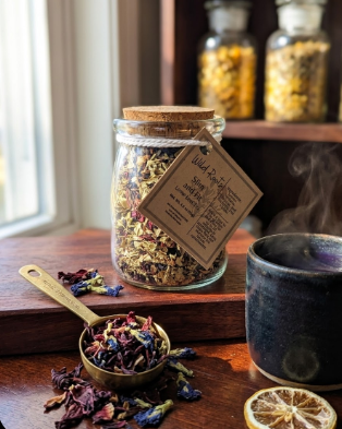 Glass jar with dried herbs and a teacup on a wooden surface