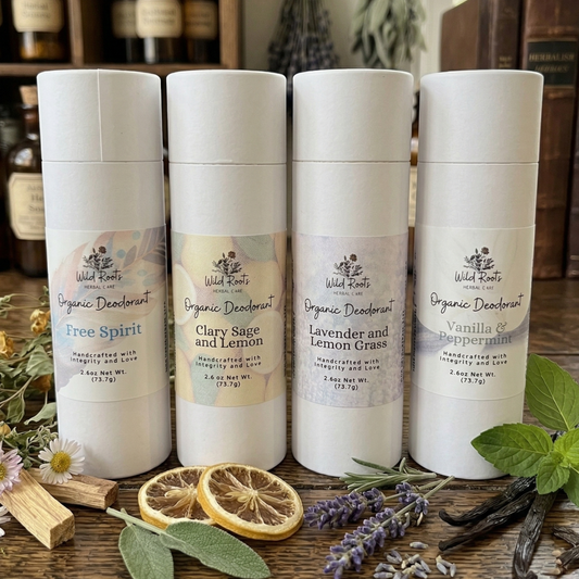 Four organic deodorant containers on a wooden surface with herbs and flowers.