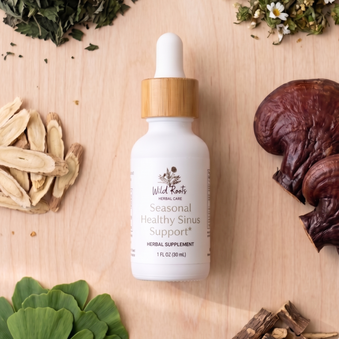 White bottle with wooden dropper labeled 'Wild Roots' on a wooden surface with herbs and plants.